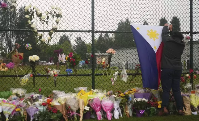 Stiv Jimenez hangs a Philippines flag at a memorial for victims after a vehicle drove into a crowd during a Filipino heritage festival in Vancouver, British Columbia, Monday, April 28, 2025. (AP Photo/Lindsey Wasson)