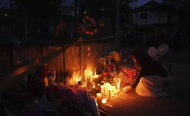 A woman pays her respects at a memorial for victims after a vehicle drove into a crowd during a Filipino heritage festival in Vancouver, British Columbia, Sunday, April 27, 2025. (AP Photo/Lindsey Wasson)