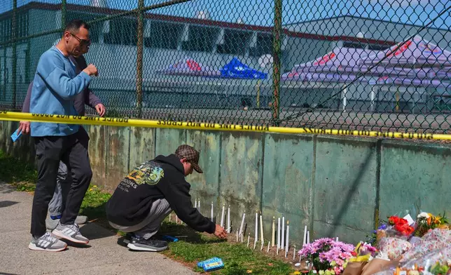 People become emotional as they light candles and gather at a growing memorial next to the scene the day after a driver killed multiple people during a Filipino community festival Sunday, April 27, 2025, in Vancouver, British Columbia. (AP Photo/Lindsey Wasson)
