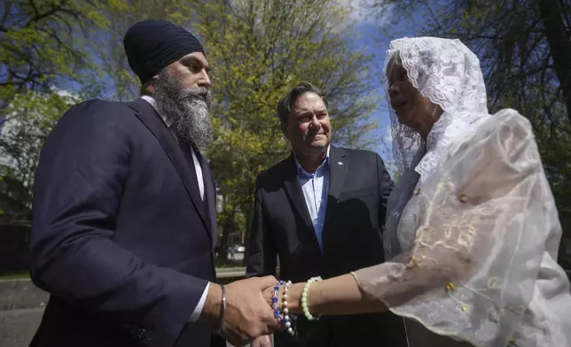 NDP Leader Jagmeet Singh talks with Rosita Taruc, right, as NDP candidate for Vancouver Kingsway Don Davies, back centre, listens as they arrive to attend mass at St. Mary's Parish after multiple people that were stuck by a car were killed at a Filipino heritage festival, in Vancouver, British Columbia, Sunday, April 27, 2025. (Darryl Dyck/The Canadian Press via AP)