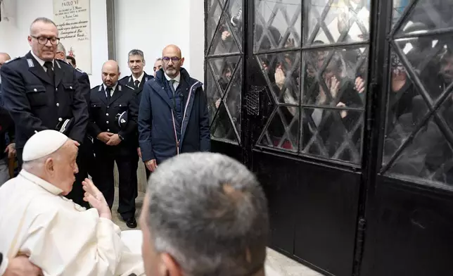 Pope Francis waves at inmates behind a closed gate during his visit to the Regina Coeli penitentiary in Rome on Holy Thursday, Thursday, April 17, 2025. (Vatican Media via AP, HO)