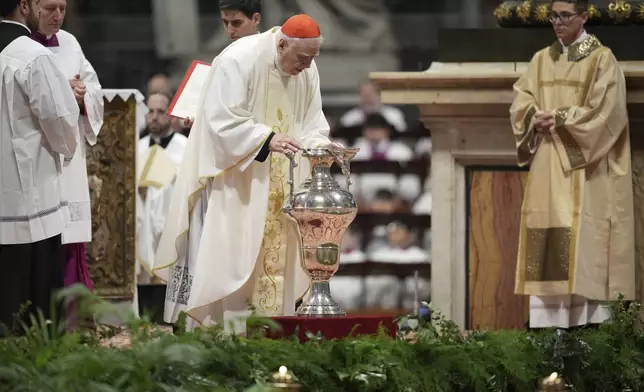 Delegate of the Holy Father, Cardinal Domenico Calcagno, center, blows inside an amphora containing holy oil during a Chrism Mass inside St. Peter's Basilica at The Vatican, Thursday, April 17, 2025. (AP Photo/Andrew Medichini)