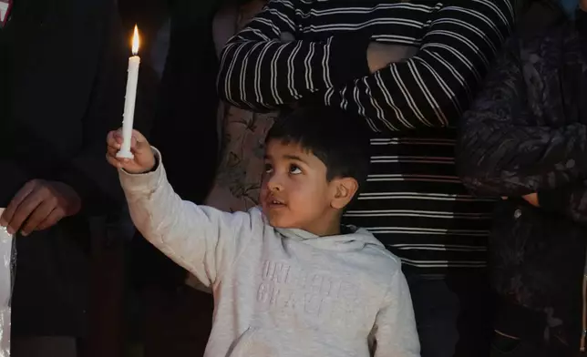 A child holds a candle during a candlelight protest in Srinagar, Indian controlled Kashmir, Wednesday, April 23, 2025, a day after an attack killed at least 26 people, most of them tourists. (AP Photo/Mukhtar Khan)