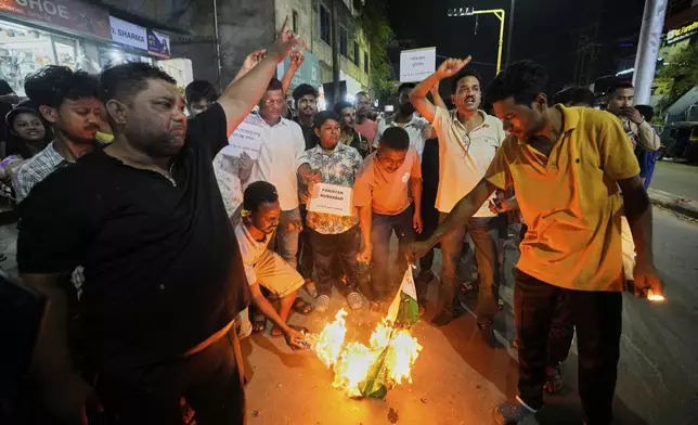 People burn a Pakistani flag in protest against the killing of tourists by militants a day after militants indiscriminately opened fire on tourists near Pahalgam in Indian controlled Kashmir, in Guwahati, India, Wednesday, April 23, 2025. (AP Photo/Anupam Nath)