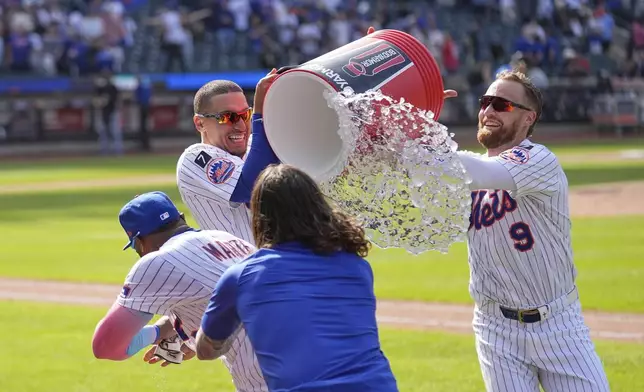 New York Mets' Tyrone Taylor, second from left, and Brandon Nimmo (9), right, try to douse Starling Marte, left, after he hit a walk off single during the tenth inning of a baseball game against the Philadelphia Phillies, Wednesday, April 23, 2025, in New York. (AP Photo/Seth Wenig)