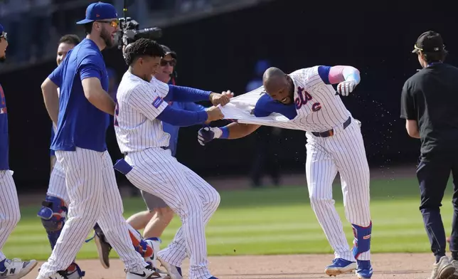 New York Mets' Starling Marte, right, celebrates with teammates after hitting a walk-off single during the tenth inning of a baseball game against the Philadelphia Phillies, Wednesday, April 23, 2025, in New York. (AP Photo/Seth Wenig)