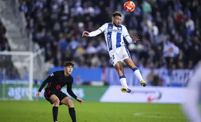 Barcelona's Pau Cubarsi, left, Leganes' Munir El Haddadi challenge for the ball during the Spanish La Liga soccer match between CD Leganes and Barcelona at the Butarque stadium in Leganes, outside Madrid, Spain, Saturday, April 12, 2025. (AP Photo/Manu Fernandez)