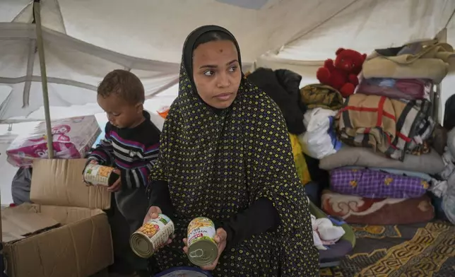 Shaima Al-Louh, 24, stores canned food for her children at her tent a makeshift camp for displaced Palestinians in Muwasi, on the outskirts of Khan Younis in the southern Gaza Strip, Wednesday, April 9, 2025. (AP Photo/Abdel Kareem Hana)
