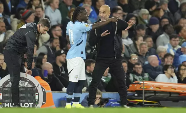 Manchester City's head coach Pep Guardiola talks with Manchester City's Jeremy Doku during the English Premier League soccer match between Manchester City and Aston Villa at Etihad stadium in Manchester, England, Tuesday, April 22, 2025. (AP Photo/Jon Super)