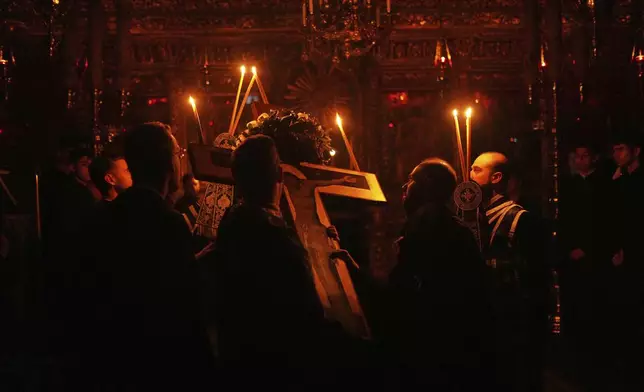 A Greek Christian Orthodox priest carries a wooden cross during the service of the Holy Passion at the Patriarchal Church of St. George, in Istanbul, Turkey, Thursday, April 17, 2025. (AP Photo/Francisco Seco)