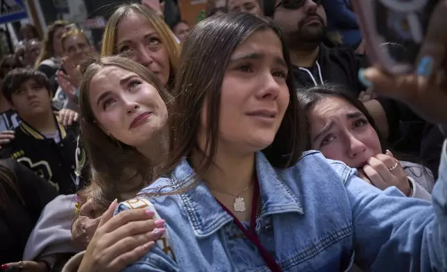 Worshipers react in tears while looking at the Christ of 'El Cerro' brotherhood as they process through the streets of Seville, during Holy Week in Spain, Tuesday, April 15, 2025. (AP Photo/Emilio Morenatti)
