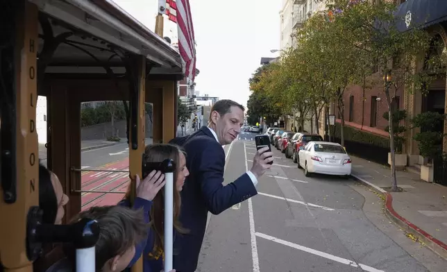 FILE - Mayor-elect Daniel Lurie, right, takes a photograph of his family while riding a cable car, before being inaugurated into office Wednesday, Jan. 8, 2025, in San Francisco. (AP Photo/Godofredo A. Vásquez, File)