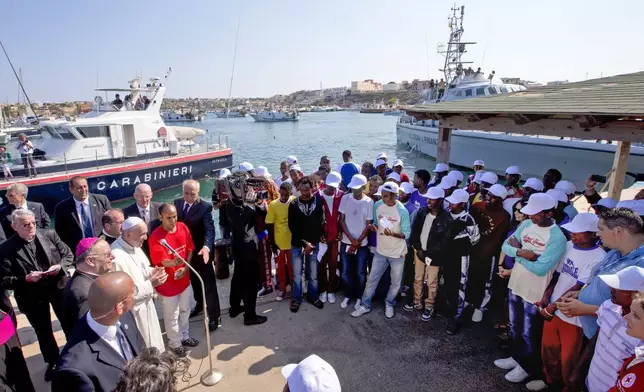 FILE-- Pope Francis, left, speaks to migrants, wearing white caps, during his visit to the island of Lampedusa, Sicily, in southern Italy, July 8, 2013. (AP Photo/Alessandra Tarantino, Pool, File)