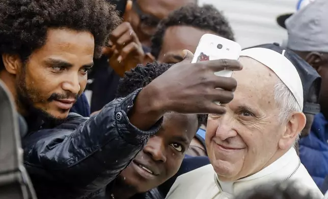 FILE - Pope Francis poses for selfie photos with migrants at a regional migrant center in Bologna, Italy, Oct. 1, 2017. (AP Photo/Luca Bruno, File)