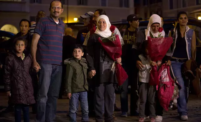 FILE - Syrian refugees Wafa, no last name available, and her husband, Osama, hold their children's hands as they arrive with another Syrian family at the St. Egidio Community in Rome, April 16, 2016. (AP Photo/Alessandra Tarantino, File)
