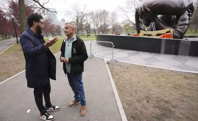 Wayne Lucas, right, who sixty years ago participated at the Freedom Rally on Boston Common, talks with Imari Paris Jeffries, the president and CEO of Embrace Boston, at the "The Embrace" sculpture on the common, Tuesday, April 15, 2025, in Boston. (AP Photo/Charles Krupa)
