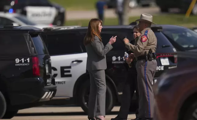 Superintendent Stephanie Elizalde, left center, speaks with a highway patrolman outside Wilmer-Hutchins High School after authorities reported the campus had been secured following reports of a shooting, in Dallas, Tx., Tuesday, April 15, 2025. (AP Photo/Julio Cortez)