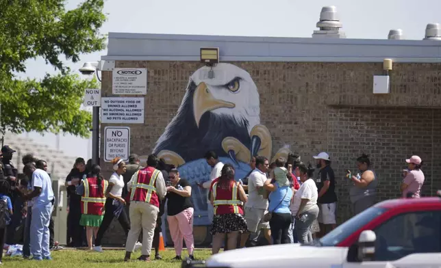 Parents are checked in to pick up their children at Wilmer-Hutchins High School, where police are responded to reports of a shooting in Dallas, Tx., Tuesday, April 15, 2025. (AP Photo/Julio Cortez)