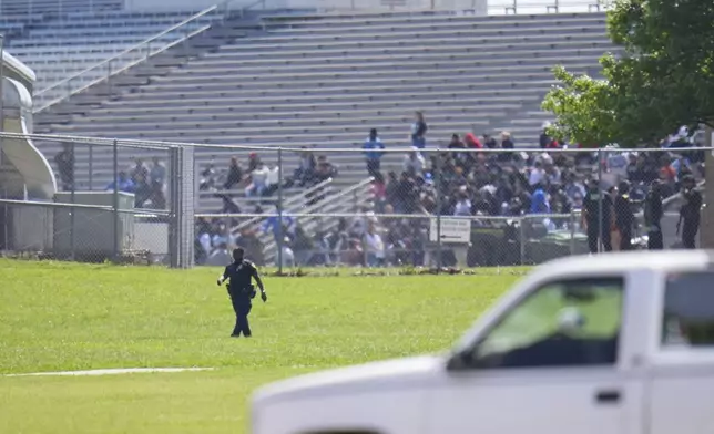 Students sit on stadium bleachers as Wilmer-Hutchins High School, where police are responding to reports of a shooting at in Dallas, Tx., Tuesday, April 15, 2025. (AP Photo/Julio Cortez)