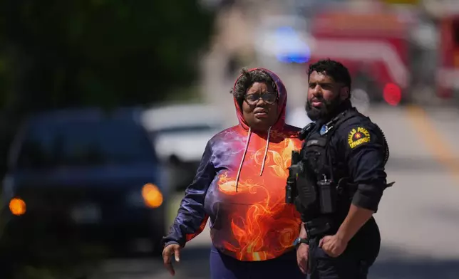 A woman arrives to a checkpoint outside Wilmer-Hutchins High School, where police are responding to reports of a shooting, in Dallas, Tx., Tuesday, April 15, 2025. (AP Photo/Julio Cortez)