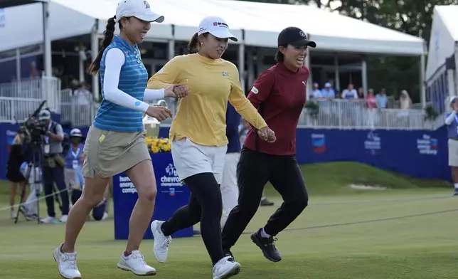 Mao Saigo, of Japan, in yellow, prepares to dive into the water off the 18th green after winning the Chevron Championship LPGA golf tournament Sunday, April 27, 2025, in The Woodlands, Texas. (AP Photo/Ashley Landis)