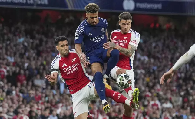 PSG's Desire Doue vies for the ball with Arsenal's Mikel Merino and Jakub Kiwior, right, during the Champions League semifinal first leg soccer match between Arsenal and Paris Saint-Germain at Arsenal Stadium in London, England, Tuesday, April 29, 2025. (AP Photo/Kin Cheung)