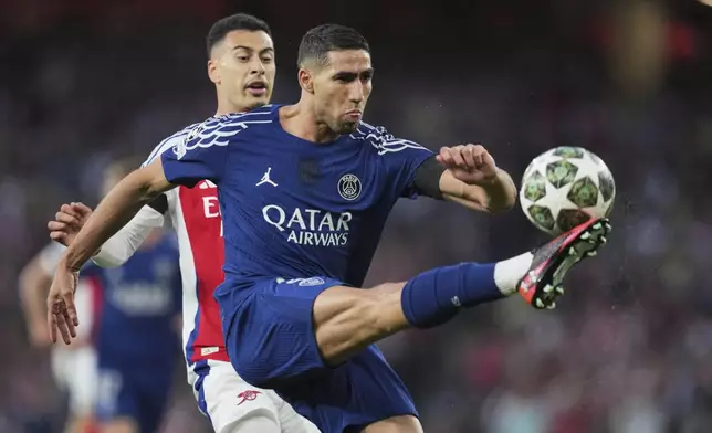 PSG's Achraf Hakimi reaches for the ball in front of Arsenal's Gabriel Martinelli during the Champions League semifinal first leg soccer match between Arsenal and Paris Saint-Germain at Arsenal Stadium in London, England, Tuesday, April 29, 2025. (AP Photo/Kin Cheung)