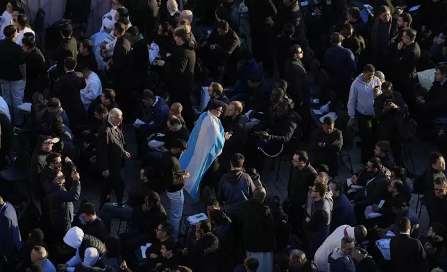 A faithful wearing a flag from Argentina arrives for the funeral of Pope Francis in St. Peter's Square at the Vatican, Saturday, April 26, 2025. (AP Photo/Gregorio Borgia)