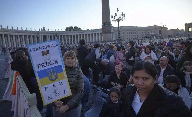 Faithful, one holding a placard with the Ukrainian flag and reading Francis, pray for us, arrive for the funeral of Pope Francis in St. Peter's Square at the Vatican, Saturday, April 26, 2025. (AP Photo/Alessandra Tarantino)