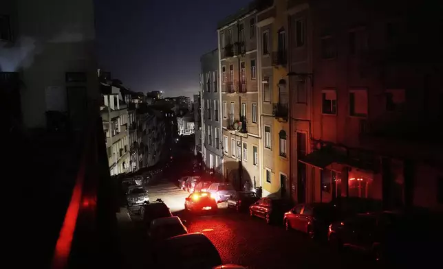 A car drives down an unlit street in Lisbon, during a nationwide power outage, Monday night, April 28, 2025. (AP Photo/Armando Franca)