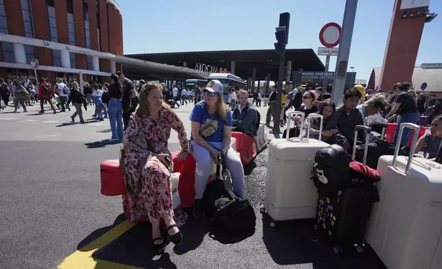 Passengers wait outside Atocha train station during a nationwide power outage in Madrid, Monday, April 28, 2025. (AP Photo/Manu Fernandez)