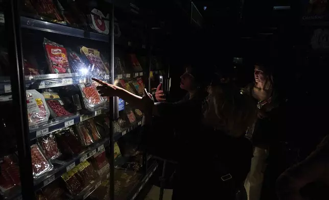 People buy food at a supermarket during a massive power outage in Pamplona, northern Spain, Monday, April 28, 2025. (AP Photo/Miguel Oses)