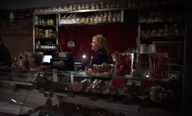 Vendors use their phone light to select and save some food, during a major power outage in Barcelona, Spain, Monday, April 28, 2025. (AP Photo/Emilio Morenatti)
