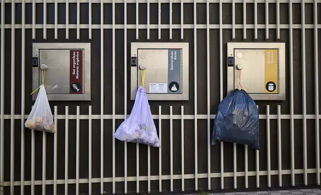 Garbage bags hang from the doors of electric recycling bins during a massive power outage in Pamplona, northern Spain, Monday, April 28, 2025. (AP Photo/Miguel Oses)