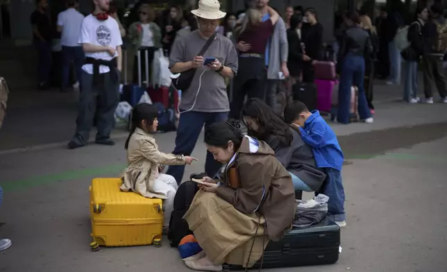 People wait outside a closed train station, during a major power outage in Barcelona, Spain, Monday, April 28, 2025. (AP Photo/Emilio Morenatti)