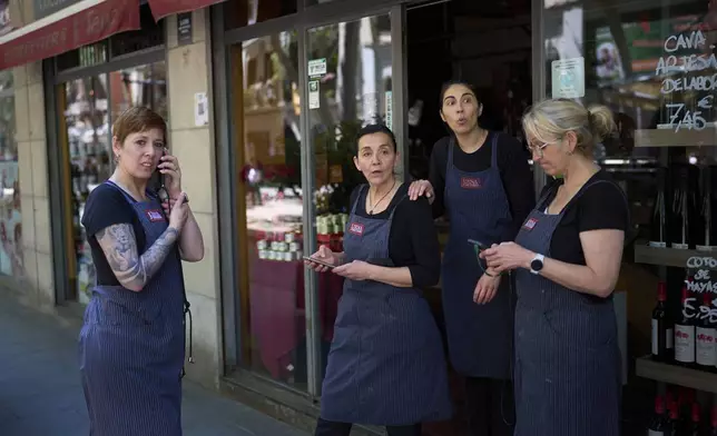 Vendors react outside their shop, during a major power outage in Barcelona, Spain, Monday, April 28, 2025. (AP Photo/Emilio Morenatti)