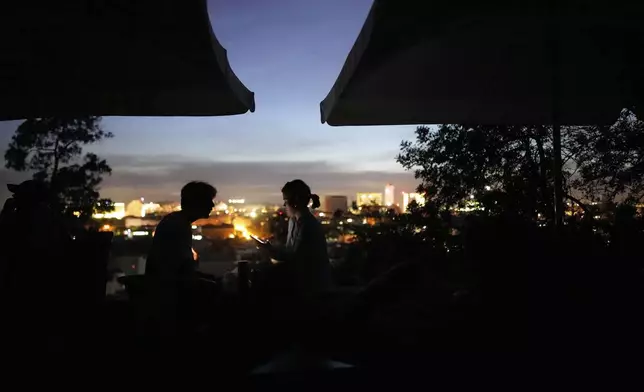 A young couple sits on the terrace of a closed bar at a viewpoint overlooking Lisbon during a nationwide power outage, Monday, April 28, 2025. (AP Photo/Armando Franca)