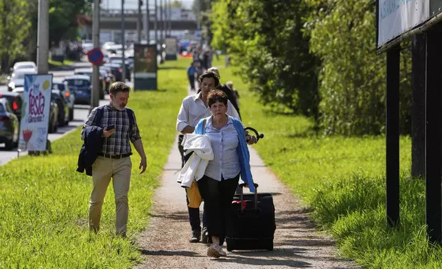 Passengers walk towards Lisbon Airport during a nationwide power outage in Lisbon, Monday, April 28, 2025. (AP Photo/Armando Franca)