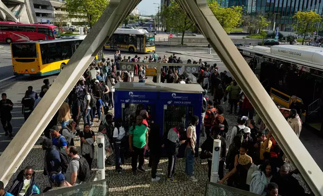 Passengers queue to catch buses at Oriente transportation hub during a nationwide power outage that stopped trains and subway in Lisbon, Monday, April 28, 2025. (AP Photo/Armando Franca)