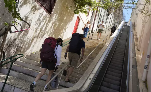 People climb stairs in Lisbon old centre after the escalator stopped working following a power outage, Monday, April 28, 2025. (AP Photo/Armando Franca)