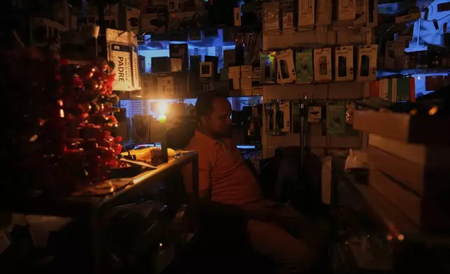 A vendor sits inside his shop during a major power outage, in Madrid, Monday, April 28, 2025. (AP Photo/Manu Fernandez)