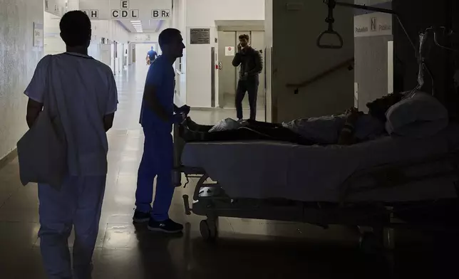 A medical staffer relocates a patient during a nationwide power outage in Pamplona, northern Spain, Monday, April 28, 2025. (AP Photo/Miguel Oses)