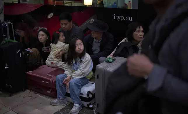 Passengers sit as they wait for news of train departures, at Sants train station in Barcelona, Spain, Tuesday, April 29, 2025. (AP Photo/Emilio Morenatti)
