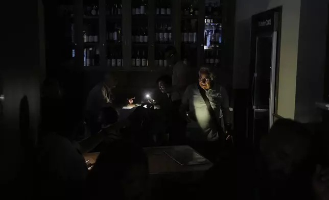 People eat inside a restaurant during a massive power outage in Madrid, Monday, April 28, 2025. (AP Photo/Manu Fernandez)