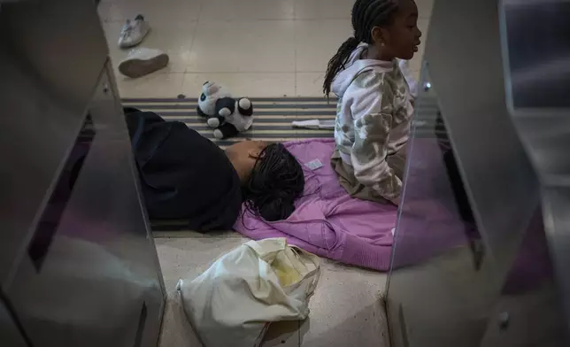 Passengers sleep and sit on the ground as they wait for news of train departures, at Sants train station in Barcelona, Spain, Tuesday, April 29, 2025. (AP Photo/Emilio Morenatti)