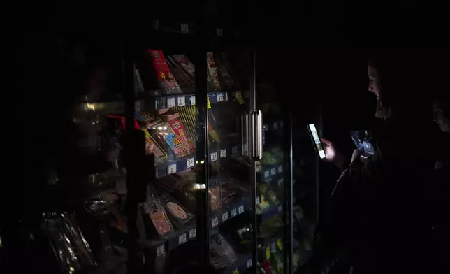 People buy food at a supermarket during a massive power outage in Pamplona, northern Spain, Monday, April 28, 2025. (AP Photo/Miguel Oses)