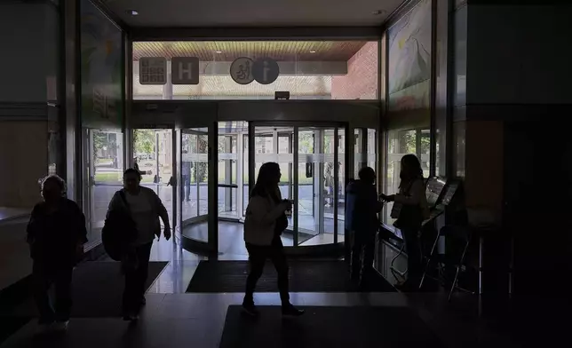 People walk inside a hospital during a nationwide power outage in Pamplona, northern Spain, Monday, April 28, 2025. (AP Photo/Miguel Oses)