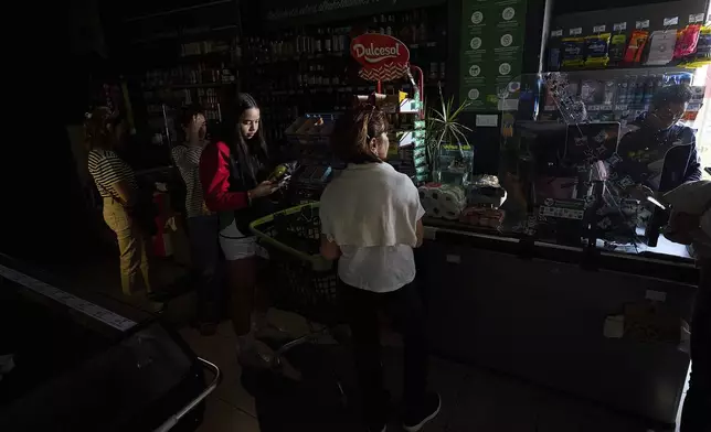 People buy food at a supermarket during a massive power outage in Pamplona, northern Spain, Monday, April 28, 2025. (AP Photo/Miguel Oses)