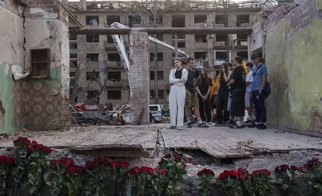 Friends of Danylo Hudya, 17, who was killed in a Thursday Russian strike, stand together in the remains of a house in a residential neighborhood in Kyiv, Ukraine, on Friday, April 25, 2025. (AP Photo/Evgeniy Maloletka)