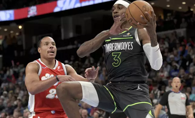 Minnesota Timberwolves forward Jaden McDaniels (3) handles the ball ahead of Memphis Grizzlies guard Desmond Bane, left, in the first half of an NBA basketball game Thursday, April 10, 2025, in Memphis, Tenn. (AP Photo/Brandon Dill)